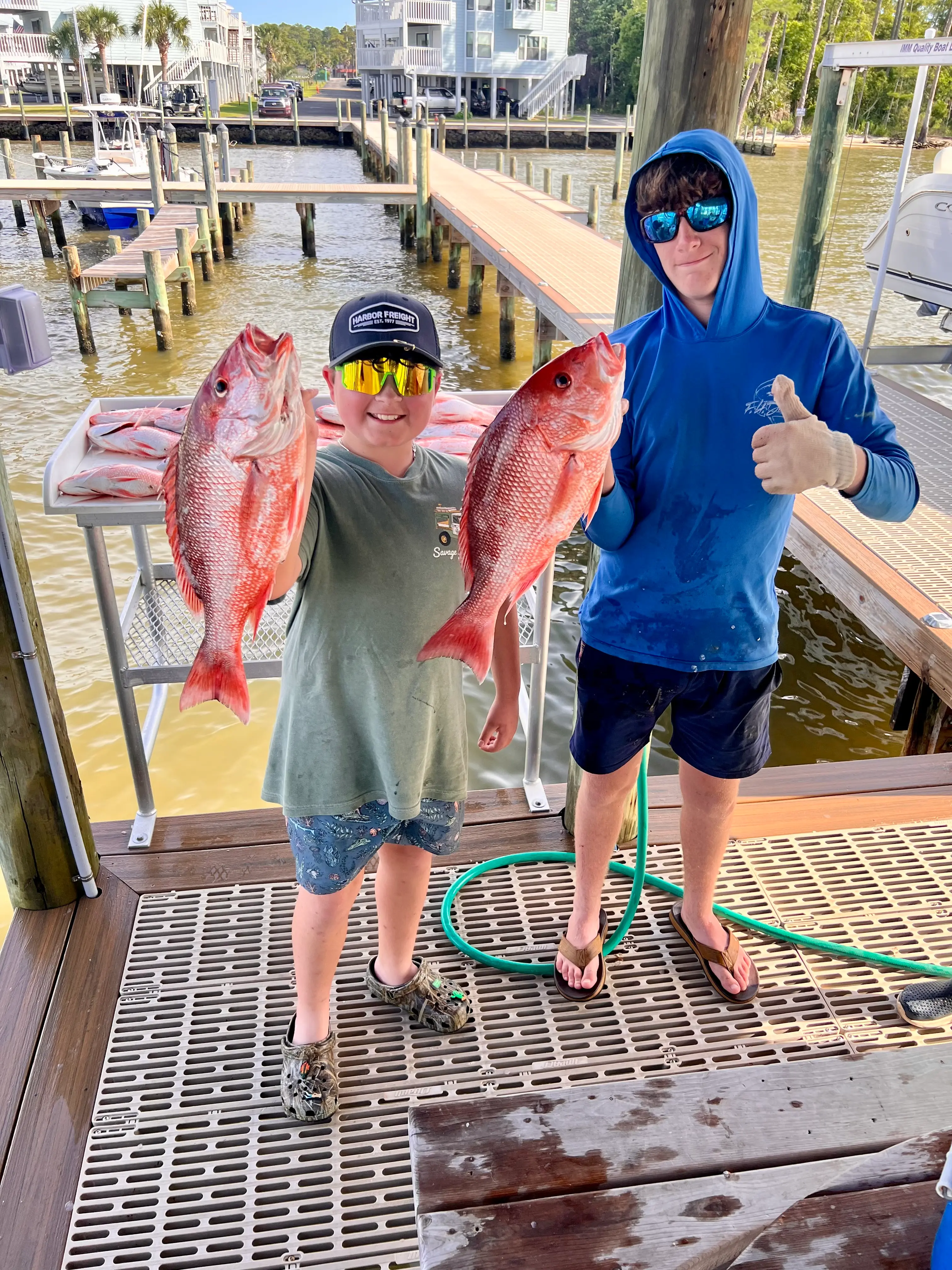 Two young anglers holding large red snapper on the dock after a Deep South Charters fishing trip in Orange Beach Alabama
